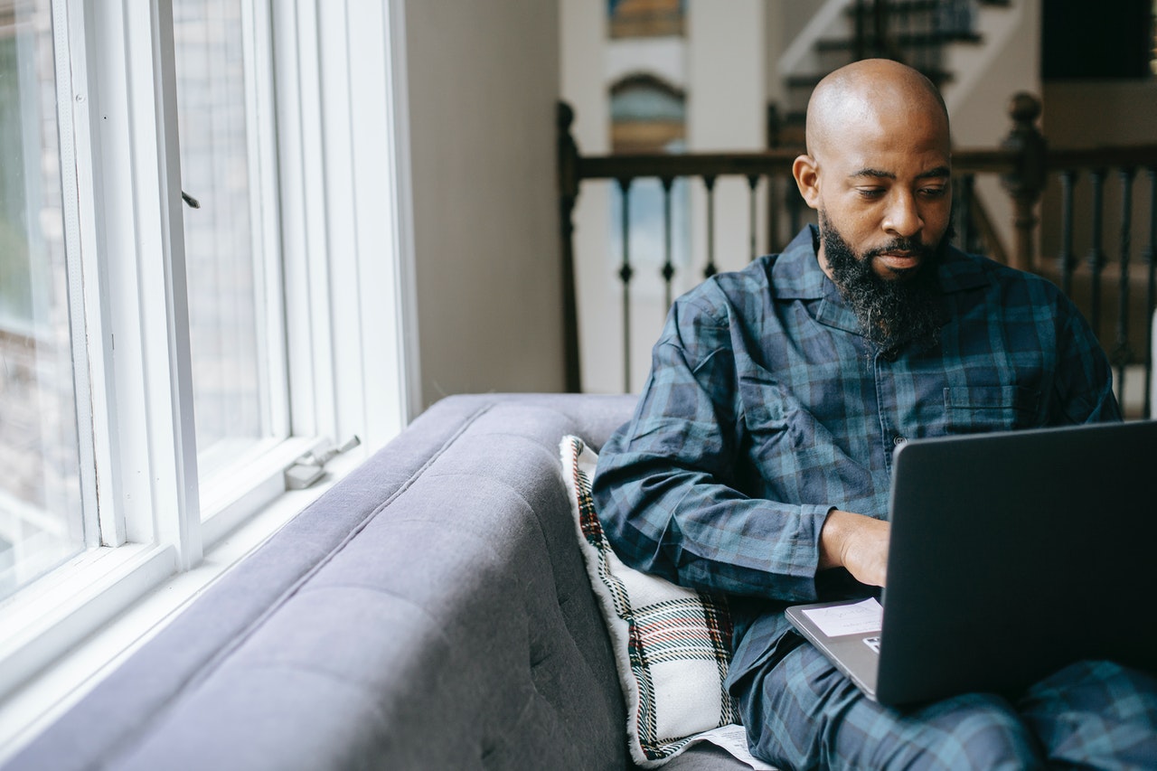 Um homem negro mexendo no computador. Imagem representando busca pelo financiamento imobiliário.