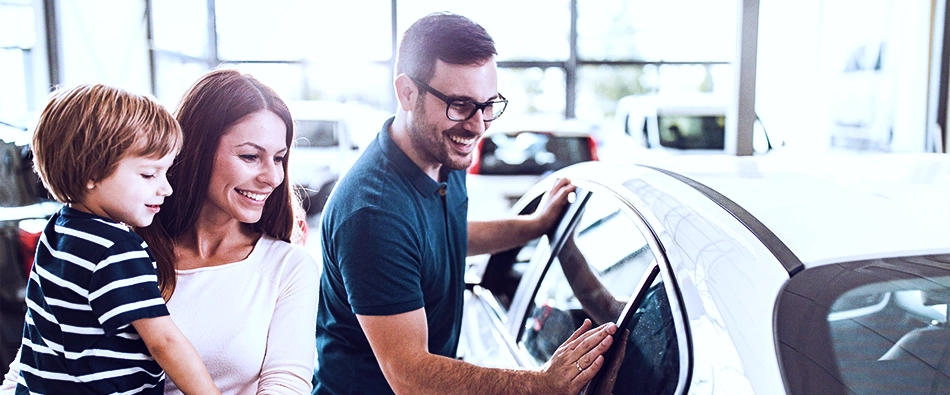 Imagem mostra uma família feliz, ao lado de um carro, depois de ter finalizado um empréstimo com garantia de veículo.